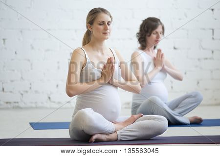 Pregnant Young Women Meditating With Hands In Namaste Gesture
