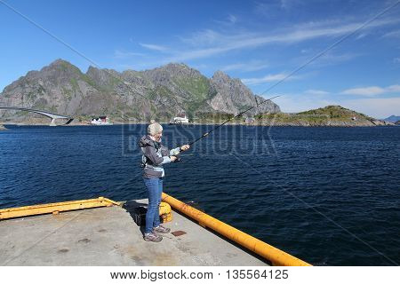 Saltwater fishing in Norway - female with a fishing rod in Lofoten islands.