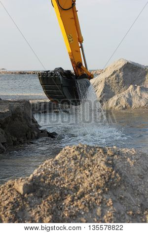 excavator loading dumper truck with sand at construction site