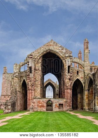 The ruins of pink colored Melrose Abbey in the Scottisch Borders region in Scotland