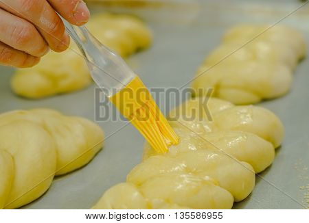 Using brush applying butter on top of beautiful kringle dough, preparing to cook in oven.