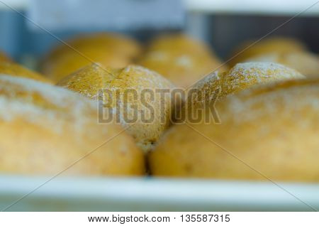Bread buns lined up cooking inside oven, beautiful golden brown color.