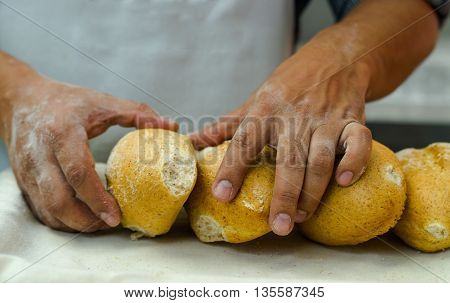 Bakers hands stacking fresh delicious buns of bread against each other.