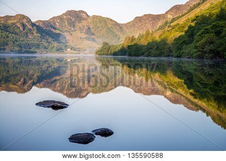 Wooded mountainside is perfectly reflected in the tranquil lake