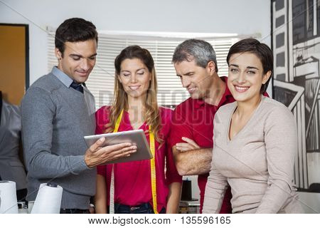 Tailor Standing With Colleagues Using Digital Tablet