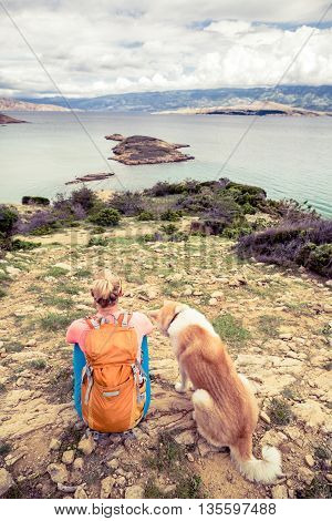 Woman hiking with akita inu dog on seaside trail. Recreation and healthy lifestyle outdoors in summer mountains and sea nature. Beautiful inspirational landscape. Trekking and activity concept.