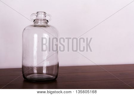Clear Glass Demijohn Against A Light Background