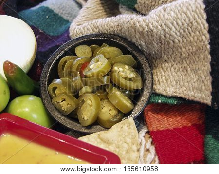 A bowl of hot jalapeno peppers with queso on the side.