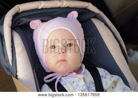 little newborn baby girl rests in the car seat in car