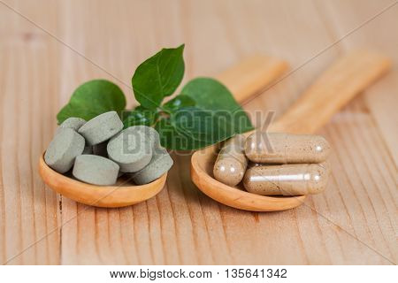 Herbal capsules on wooden spoon. herb for healthy living.