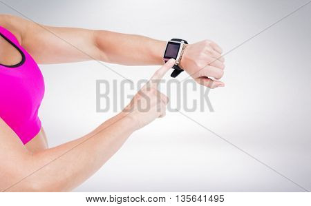 Female athlete using her smart watch against grey background