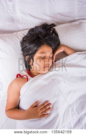 cute Indian Girl sleeping over white pillow, small asian girl sleeping on bed