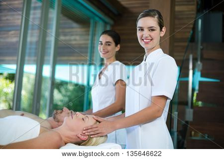 Woman receiving head massage from masseur in spa