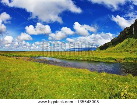 Iceland in July. Green fields and streams near the giant ice plateau