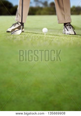Golfer placing golf ball on tee on a sunny day at the golf course