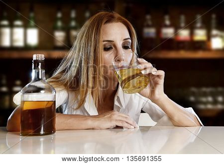 drunk woman alone in wasted and depressed face expression drinking scotch whiskey glass sitting at bar or pub in alcohol abuse and alcoholic housewife concept