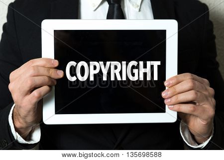 Business man holding tablet with the text: Copyright