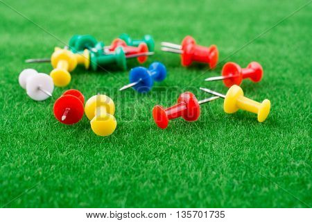 Colorful pins spred around on green grass