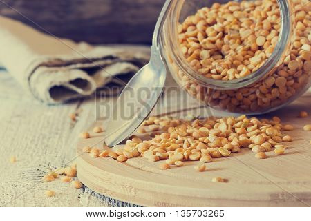 Dry peas scattered from a jar on a cutting board on a white wooden table. Close-up. Bio healthy and diet food. Selective focus . Toned inage