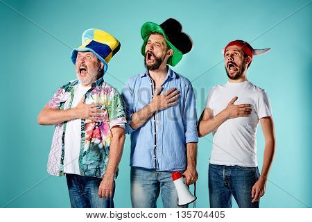 The three football fans singing the national anthem over blue background
