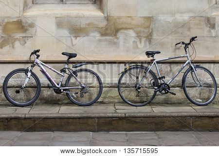 CAMBRIDGE UK - APRIL 8TH 2016: Two bicycles propped up against a wall in the university city of Cambridge in the UK on 8th April 2016. Bicycles are the quickest and cheapest mode of transport in and around the town.