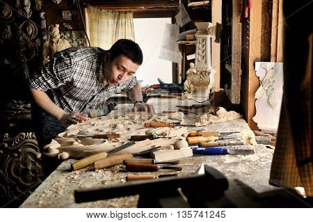 Carver in workshop of wood carving blow off sawdust