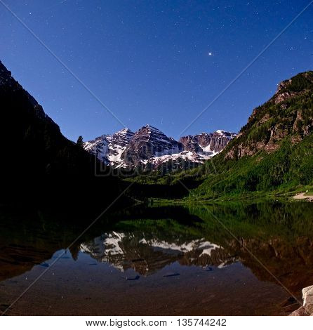 Crater Lake with reflection of Maroon Bells and starry sky at night.  Maroon Peak near Aspen and Snowmass, Colorado,  USA.