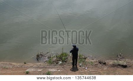 Man is fishing by spinning in the river