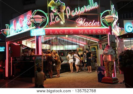 FREJUS PORT PROVENCE FRANCE - JUNE 20 2016: Customers waiting under the neon lights of an ice cream stall.