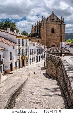 Cobble stone street in Ronda Andalucia Spain leading to a church.