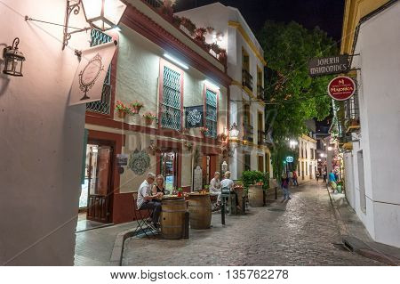 street view of summer evening in Cordoba Spain. people enjoy outdoor restaurant drinking and chatting
