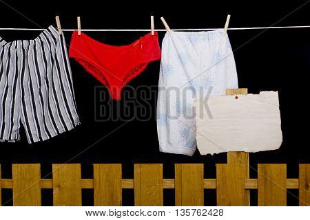 Woman panties and man underwear on clothesline on black background