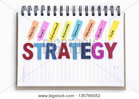 alphabet letter wood words strategy on the notebook with handwriting stability target retrenchment achievable teamwork education growth yield over white background, Business strategy concept
