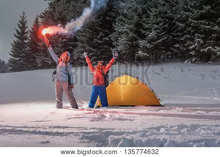 Two backpackers asking a help with rescue signal fire in a winter field