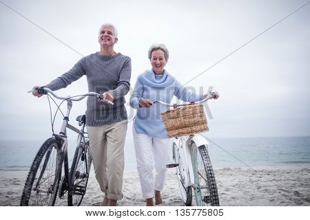 Senior couple having ride with their bike on the beach