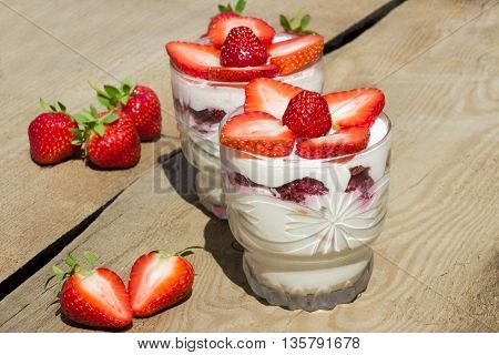Dessert with cream and fresh strawberries on wooden board