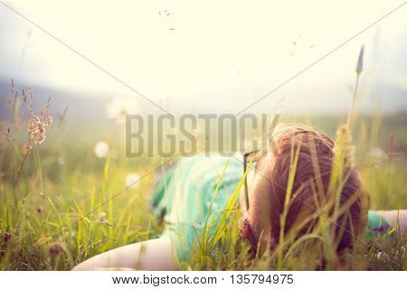 Carefree happy man lying on green grass meadow in mountains enjoying the sun on his face.Enjoying nature sunset.Freedom.Enjoyment.Relaxing in mountains at sunrise.Sunshine.Daydreaming
