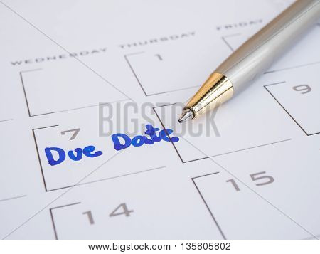 Close up handwriting word Due Date and pen on calendar desk (Selective focus)