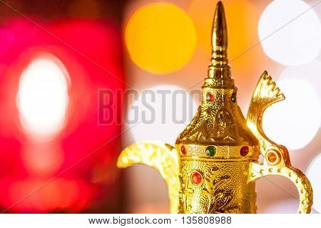 Gold Arabic Coffee pot in colorful illuminated background. Ramadan and Eid Mubarak concept background