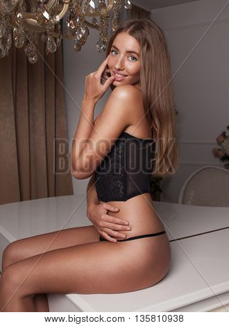 Young sexy woman in black lingerie on piano. Big boobs.