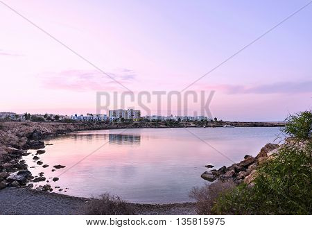 Photo of sea in protaras cyprus island with rocks and hotels at sunset.