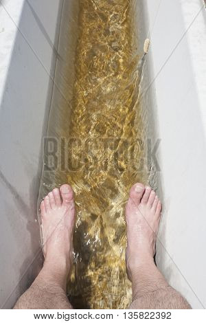 Man feet refreshing in a cool irrigation canal during the hottest day hours Vegas Altas del Guadiana Spain