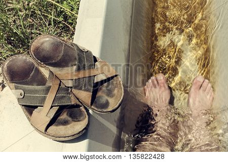 Man feet refreshing in a cool irrigation canal during the hottest day hours Vegas Altas del Guadiana Spain