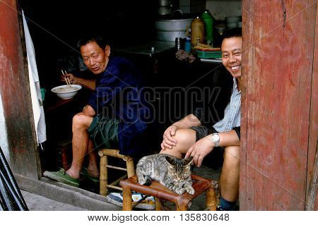 Ao Ping China - September 14 2006: Cat lounging on a bamboo stool with two merchants at their restaurant