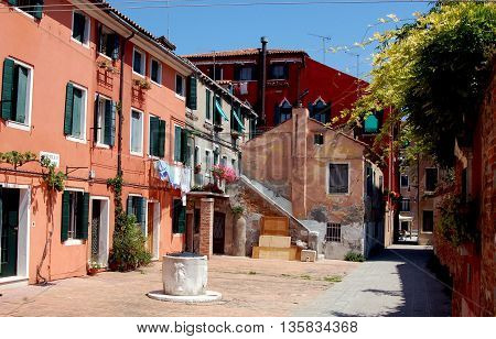 Venice, Italy - June 10, 2006:: Colourful houses some with laundry drying below the windows in a small Campiello (square)