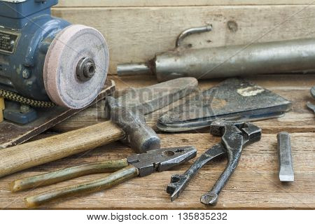 Set of old hand tools lying on a wooden bench. In the background of the winepress with an electric motor and an old pipe. The old shop.