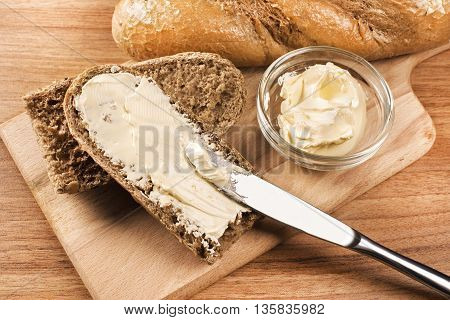 Close up a knife spreading butter on bread