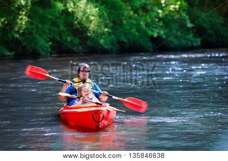 Family on kayaks and canoe tour. Father and child paddling in kayak in a river on a sunny day. Children in summer sport camp. Active preschooler kayaking in a lake. Water fun during school vacation.