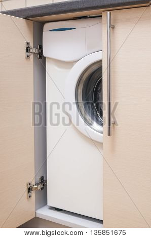 Kitchen Mini Cabinet with Portrable Washing Machine Inside. Vertical Image Composition