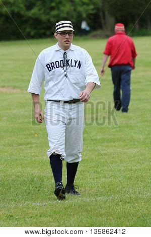 OLD BETHPAGE, NEW YORK - MAY 22, 2016: Baseball player in 19th century vintage uniform during old style base ball play following the rules and customs from 1864 in Old Bethpage Village Restoration